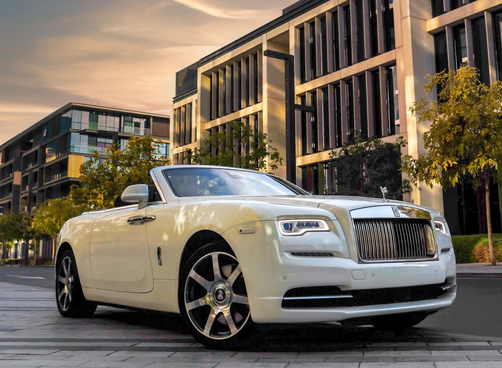 White Rolls-Royce convertible on a city street at dusk